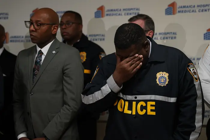 NYPD Chief of Department Jeffrey Maddrey covers his eyes as officials brief the media on the fatal shooting of an officer in Queens.